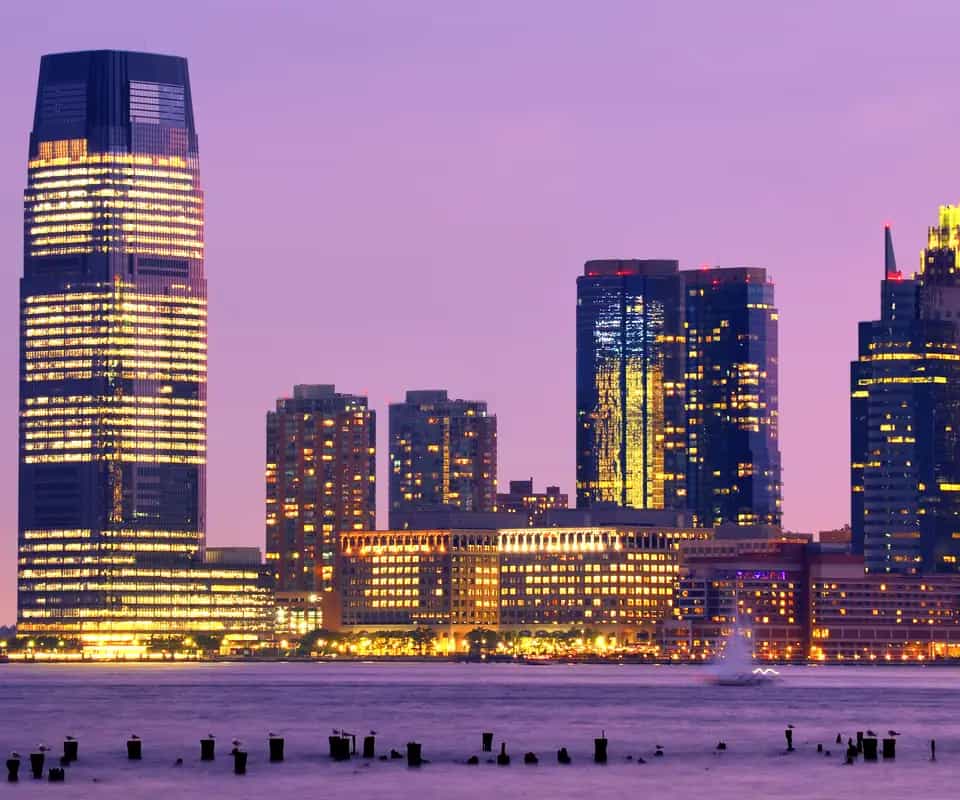 The Exchange Place towers in Jersey City at dusk, across the Hudson