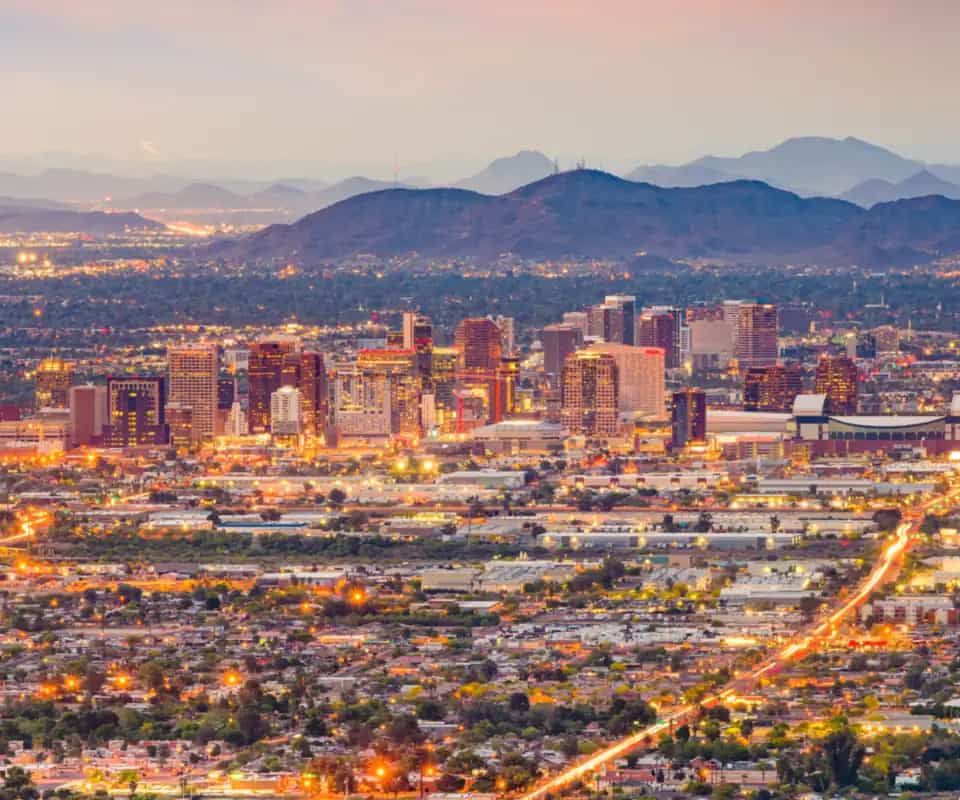 Downtown Phoenix at dusk, the valley's lights spread out around it